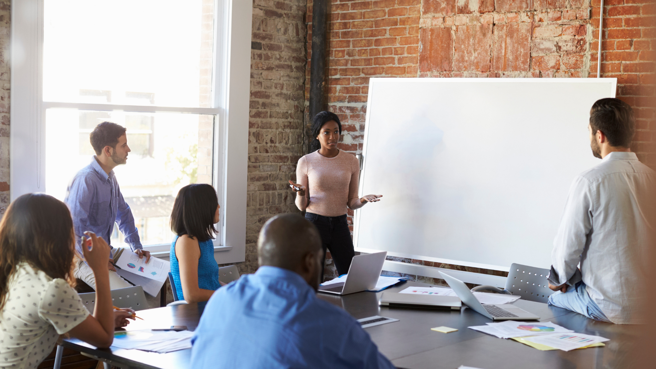 A group of six people conversing around a blank whiteboard-equity grantmaking discussion