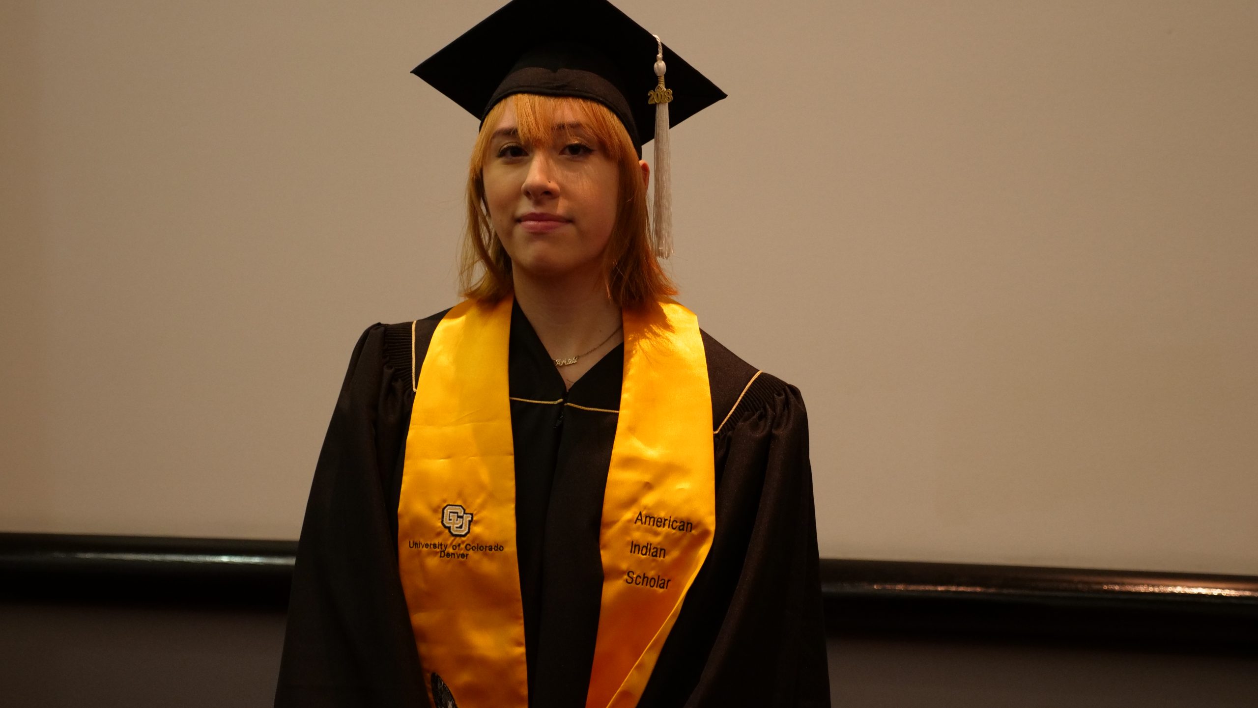 Kelsey standing in her graduation gown on graduation day.