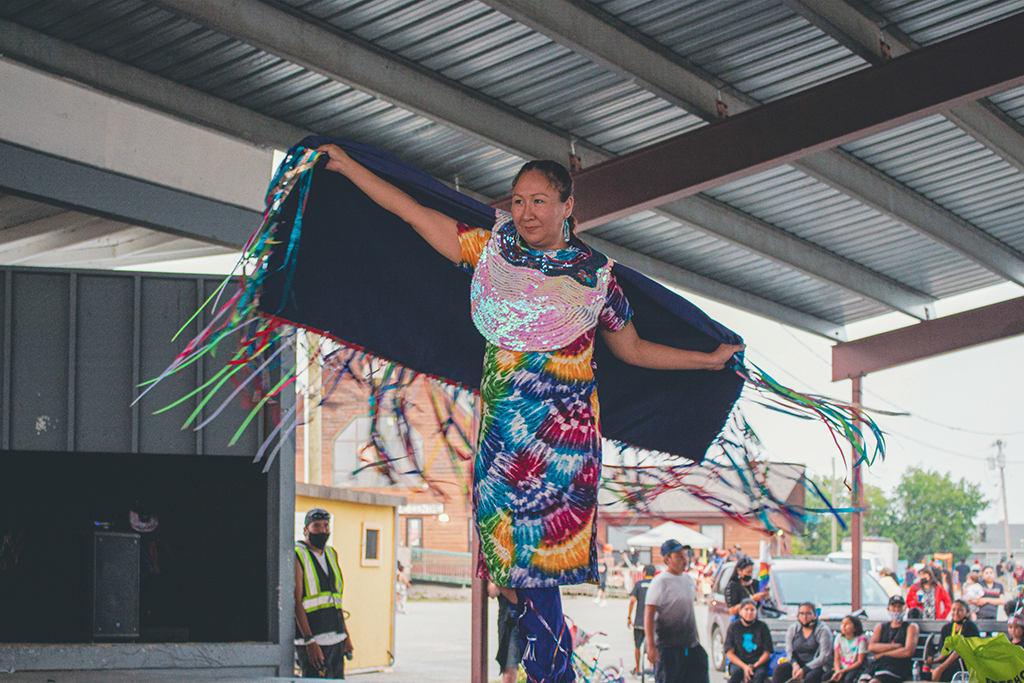 A lady performing on stage for a crowd outside.