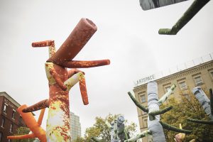 A large yellow and orange sculpture sitting outside of a park.